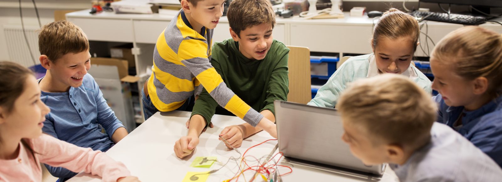 education, children, technology, science and people concept - group of happy kids with laptop computer playing with invention kit at robotics school lesson