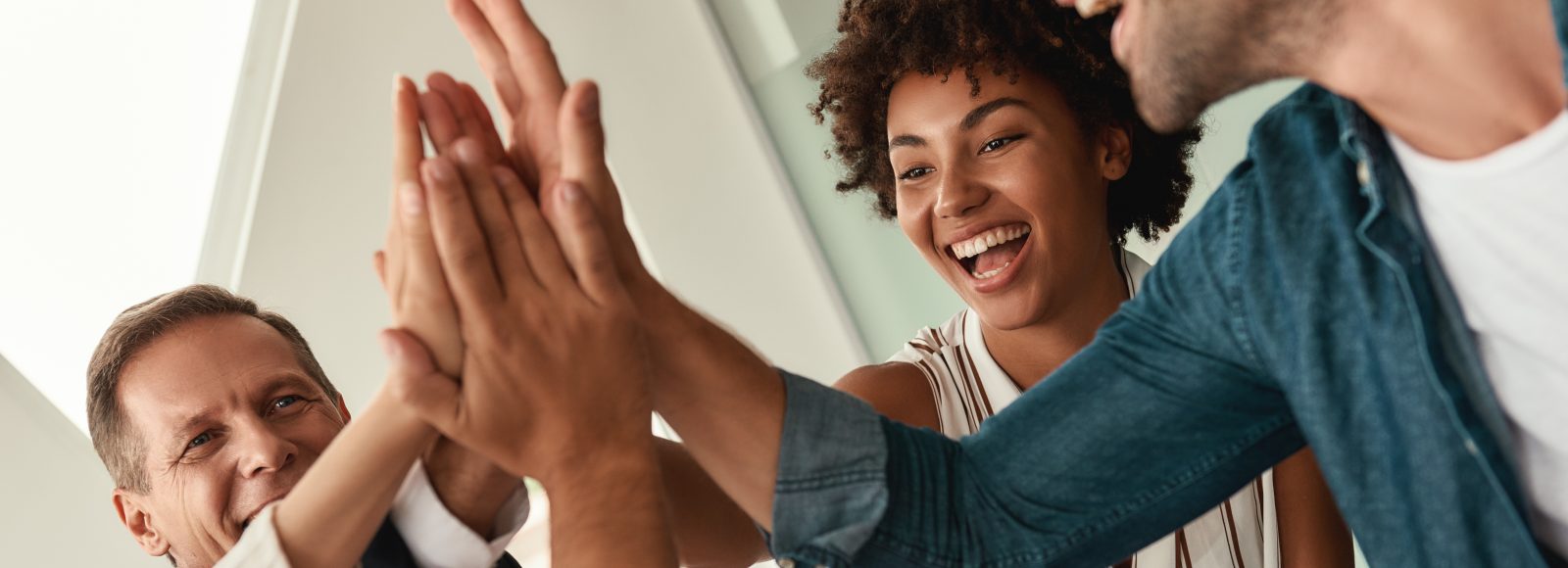 Celebrating success. Business people giving each other high-five and smiling while working together in the modern office. Teamwork